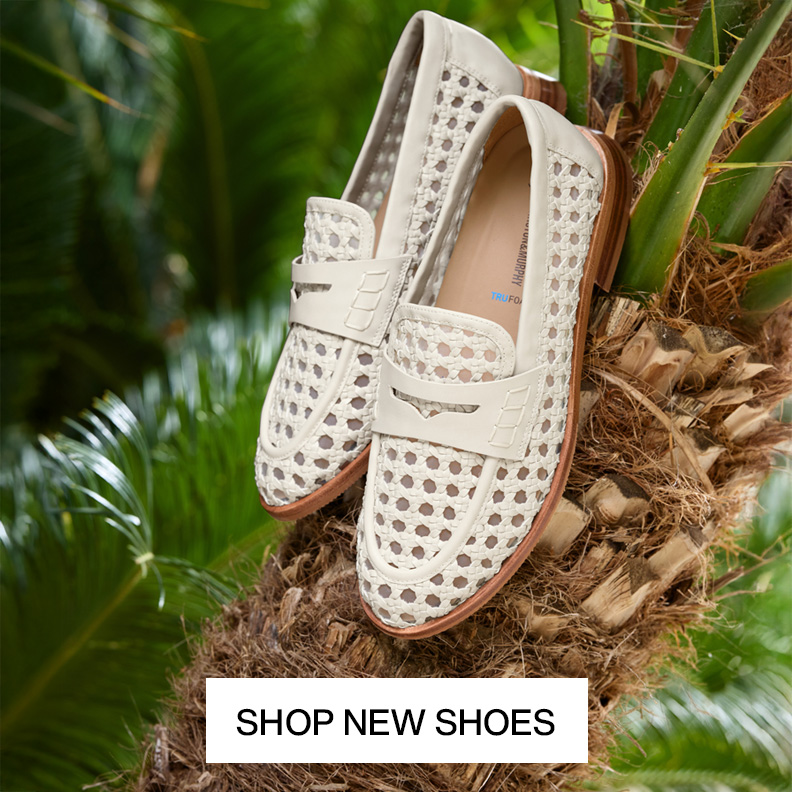 Two pairs of womens cream colored woven loafers sitting in a palm tree.