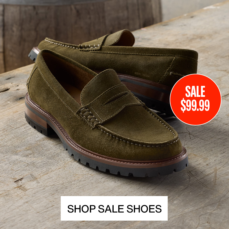 Pair of olive suede men's loafers on a wood table. 